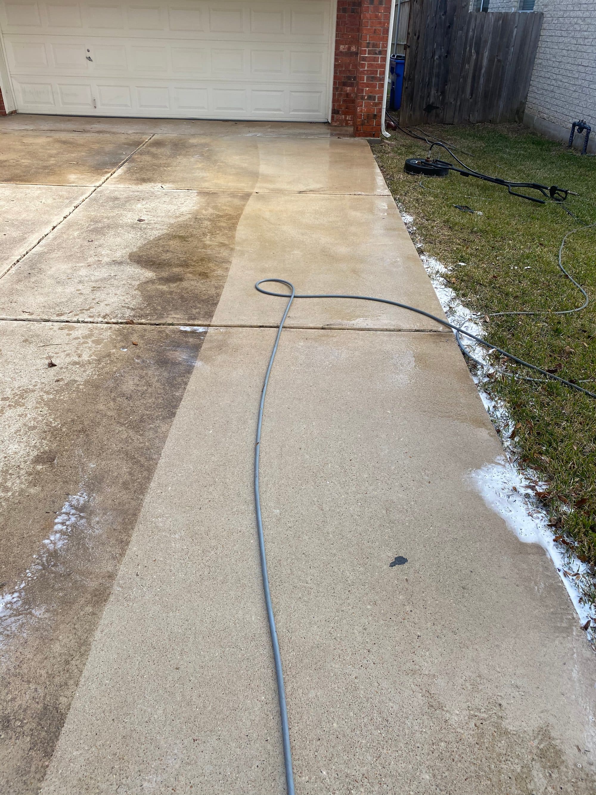 Driveway pressure washing in progress showing dramatic clean vs dirty contrast